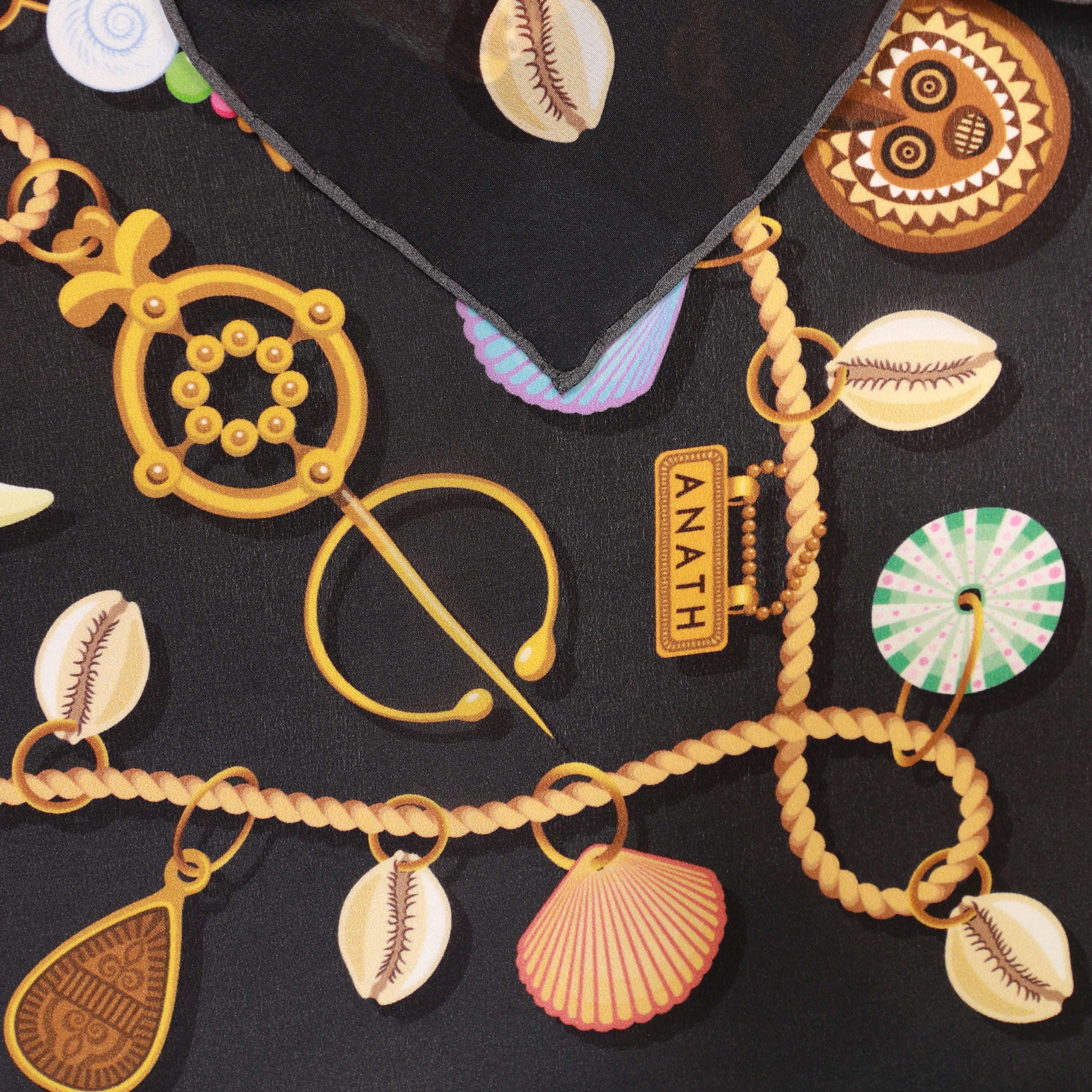 Detail of the Kauri Chloe silk bandana scarf showing hand-painted cowrie shell, chain and gemstone motifs.