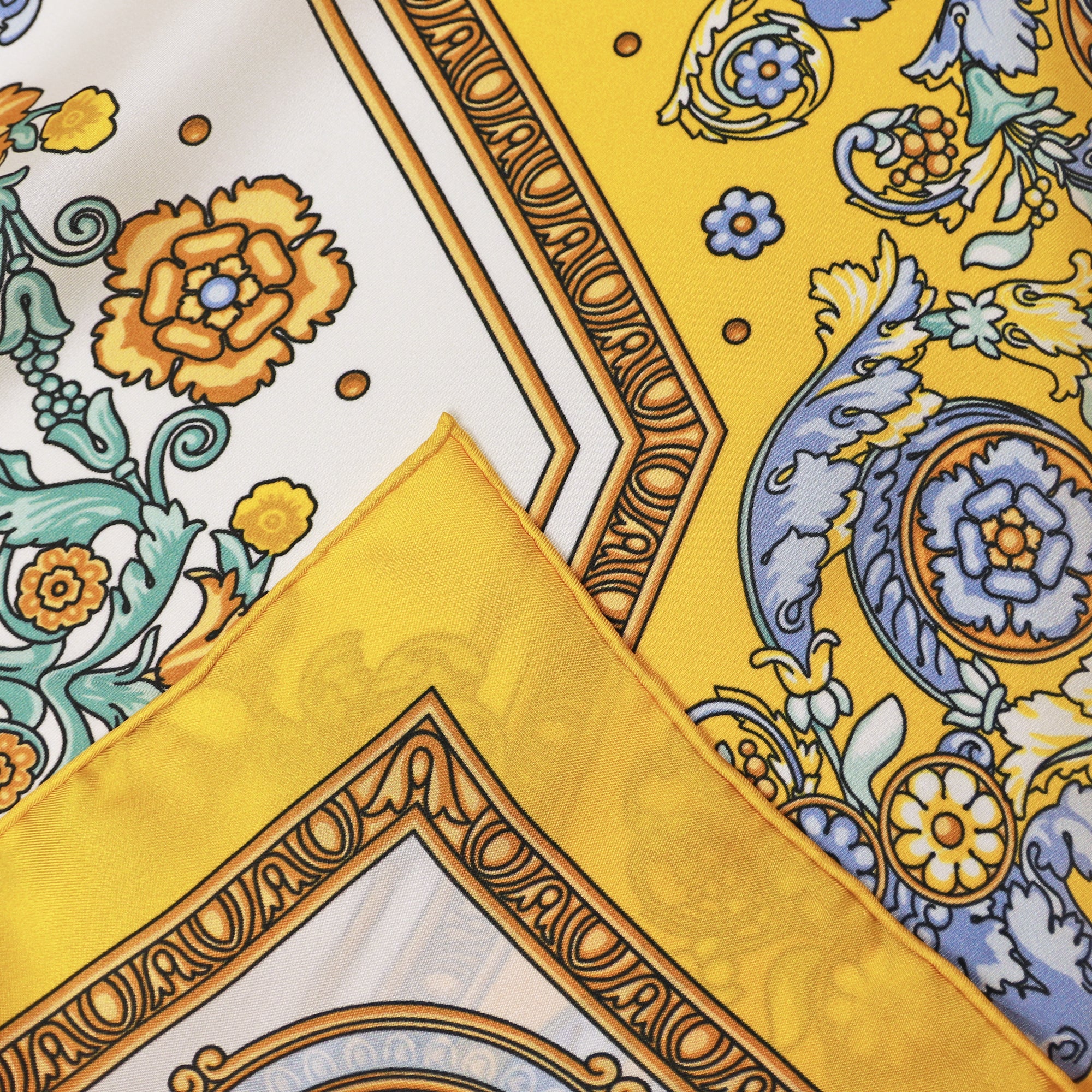 Detail of the Rococo Limone silk scarf showing floral and rococo motifs and the hand-rolled hem.