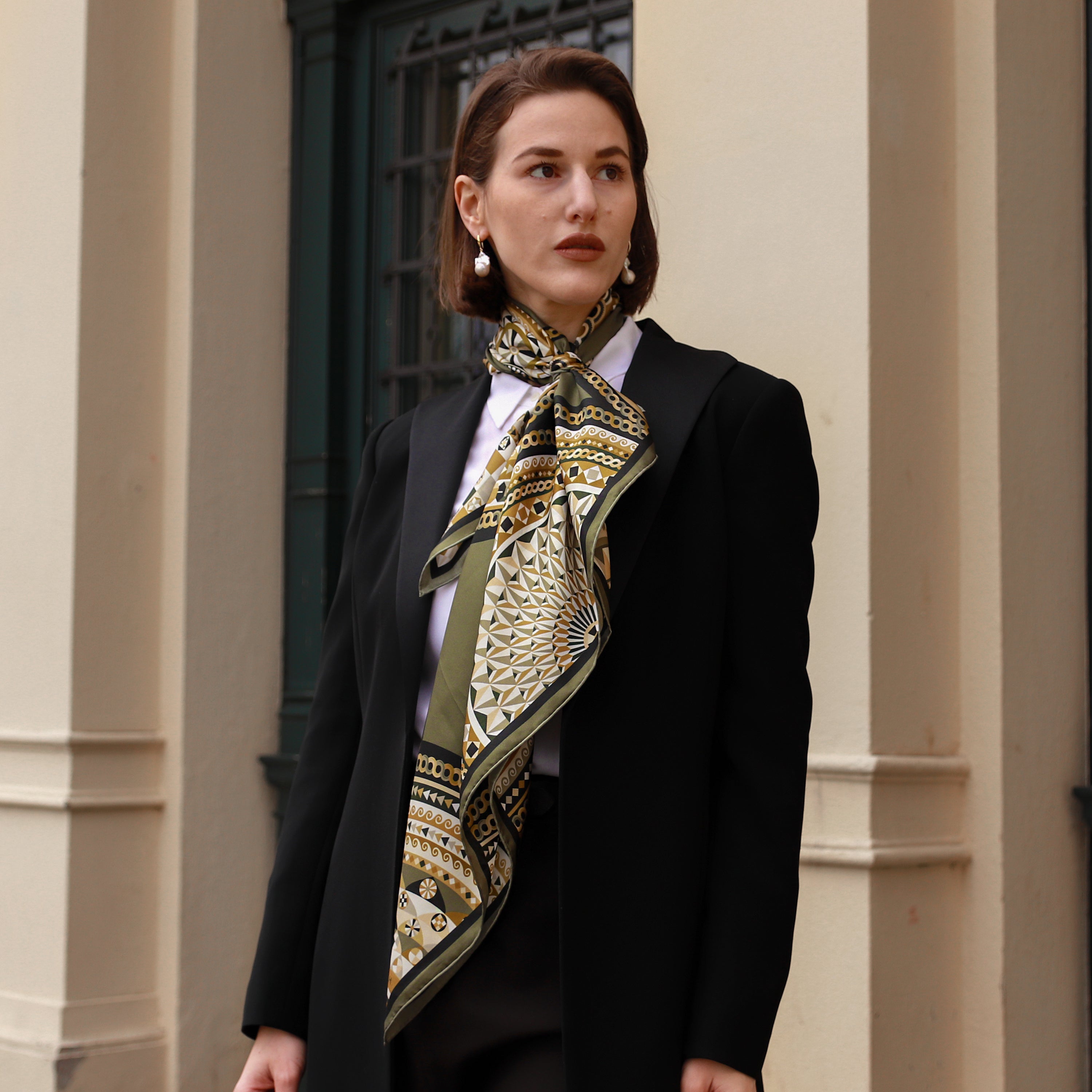 Model wearing the Basilica Nero silk scarf styled around the neck with a black blazer.