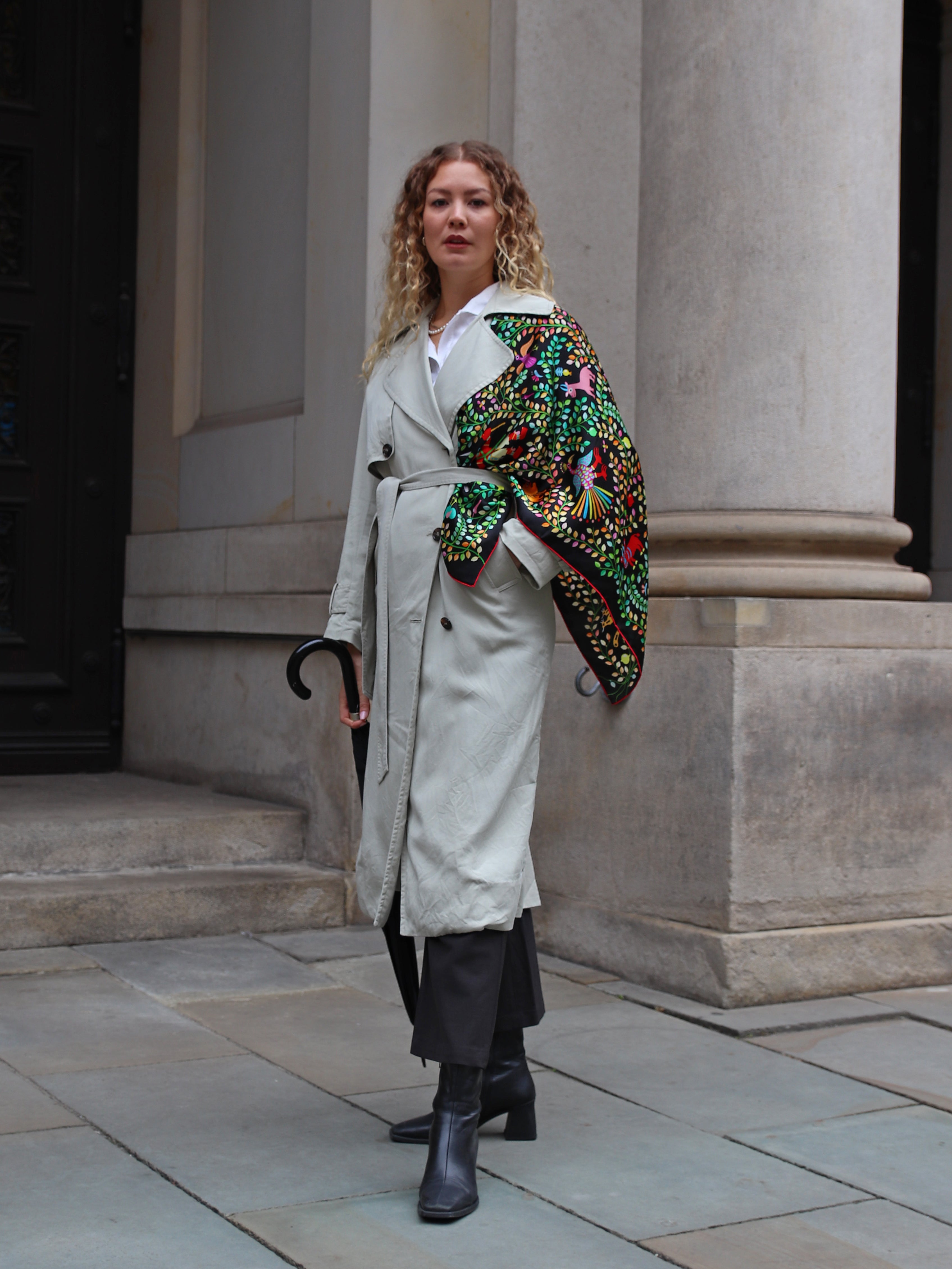Model wearing the Kings of Dahomey Original silk scarf draped over the shoulders with a light trench coat.
