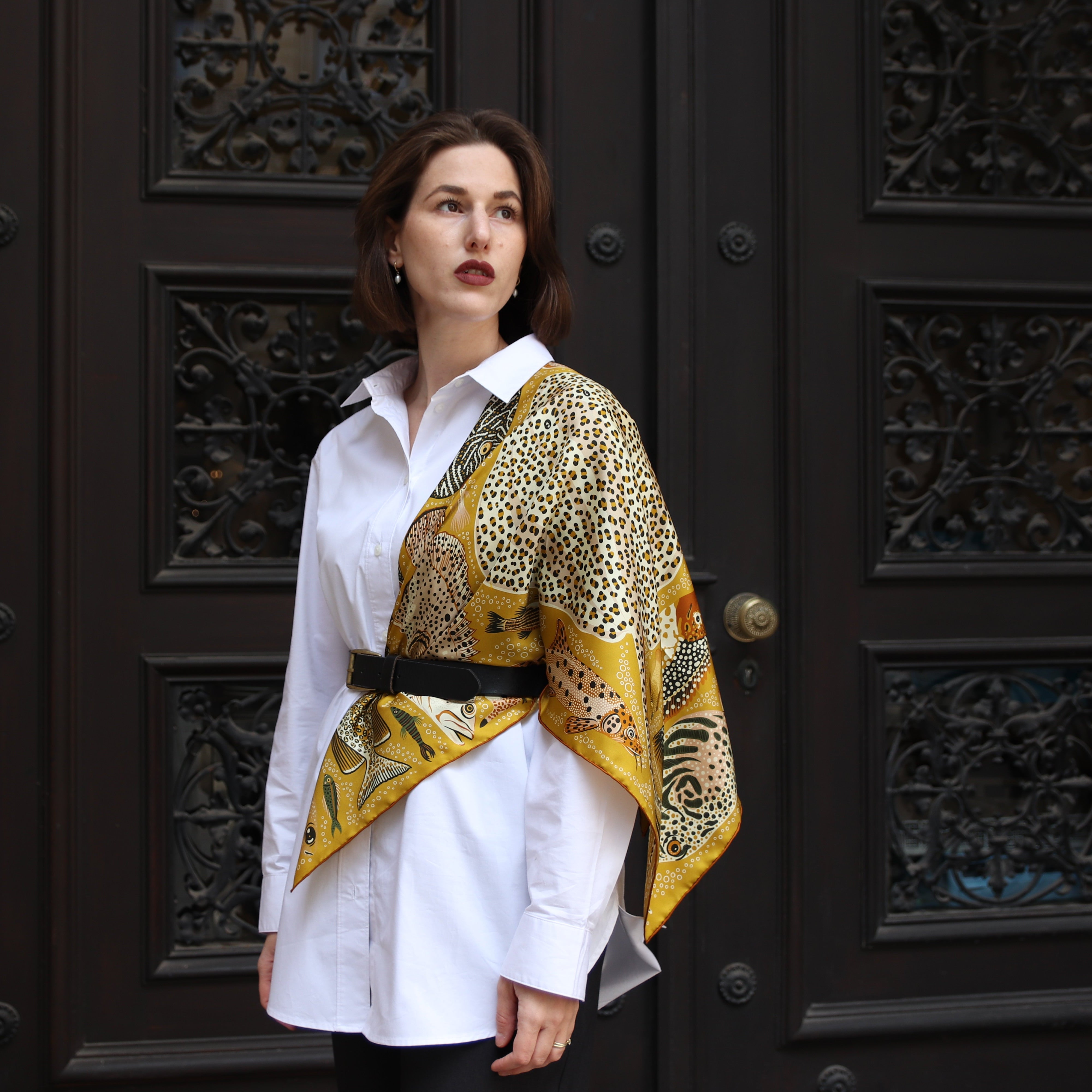 Model wearing the Pesce Miele double-sided silk scarf styled as a statement accessory with a white shirt and black belt.