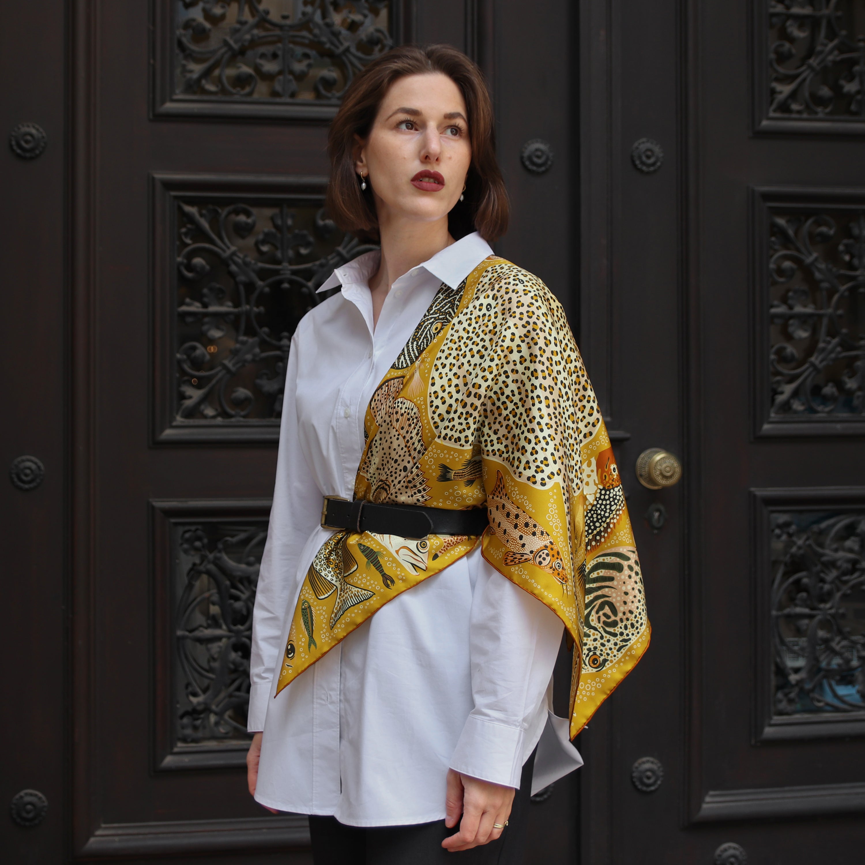 Model wearing the Pesce Miele double-sided silk scarf draped over the shoulders with a white shirt.