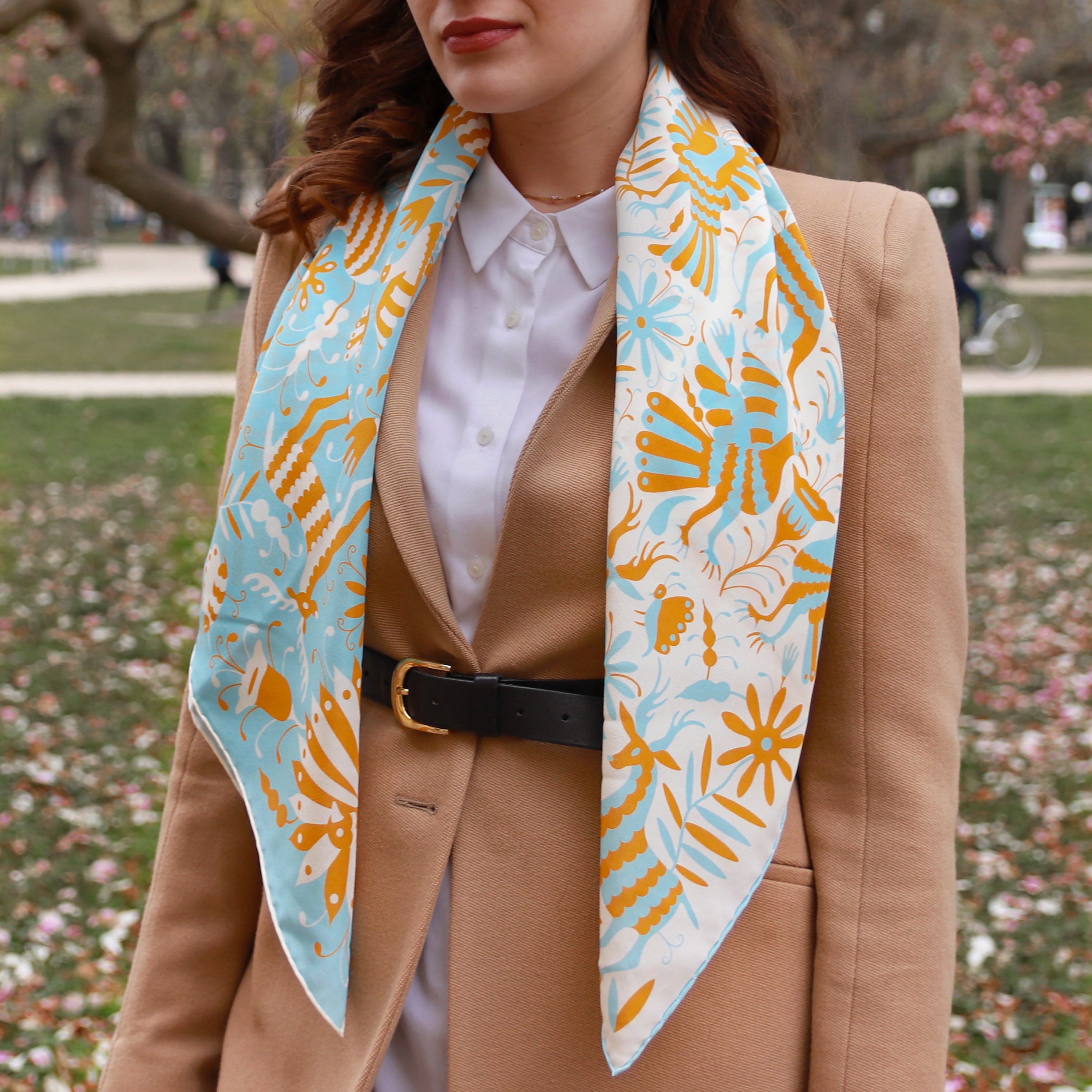 Model wearing the Noé Miroir silk scarf draped over the shoulders with a camel coat.