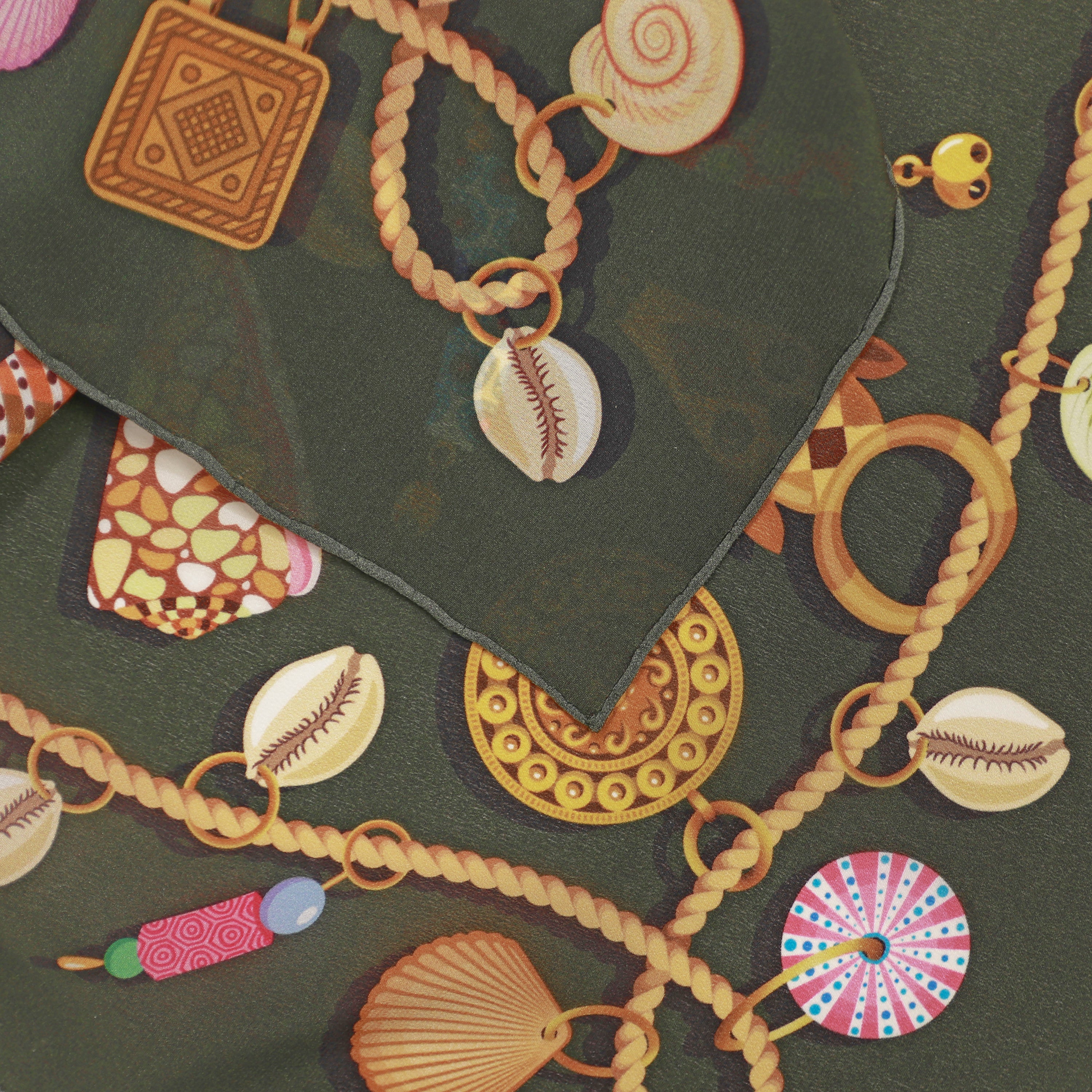 Detail of the Kauri Delphine silk bandana scarf showing hand-painted cowrie shell and chain motifs.