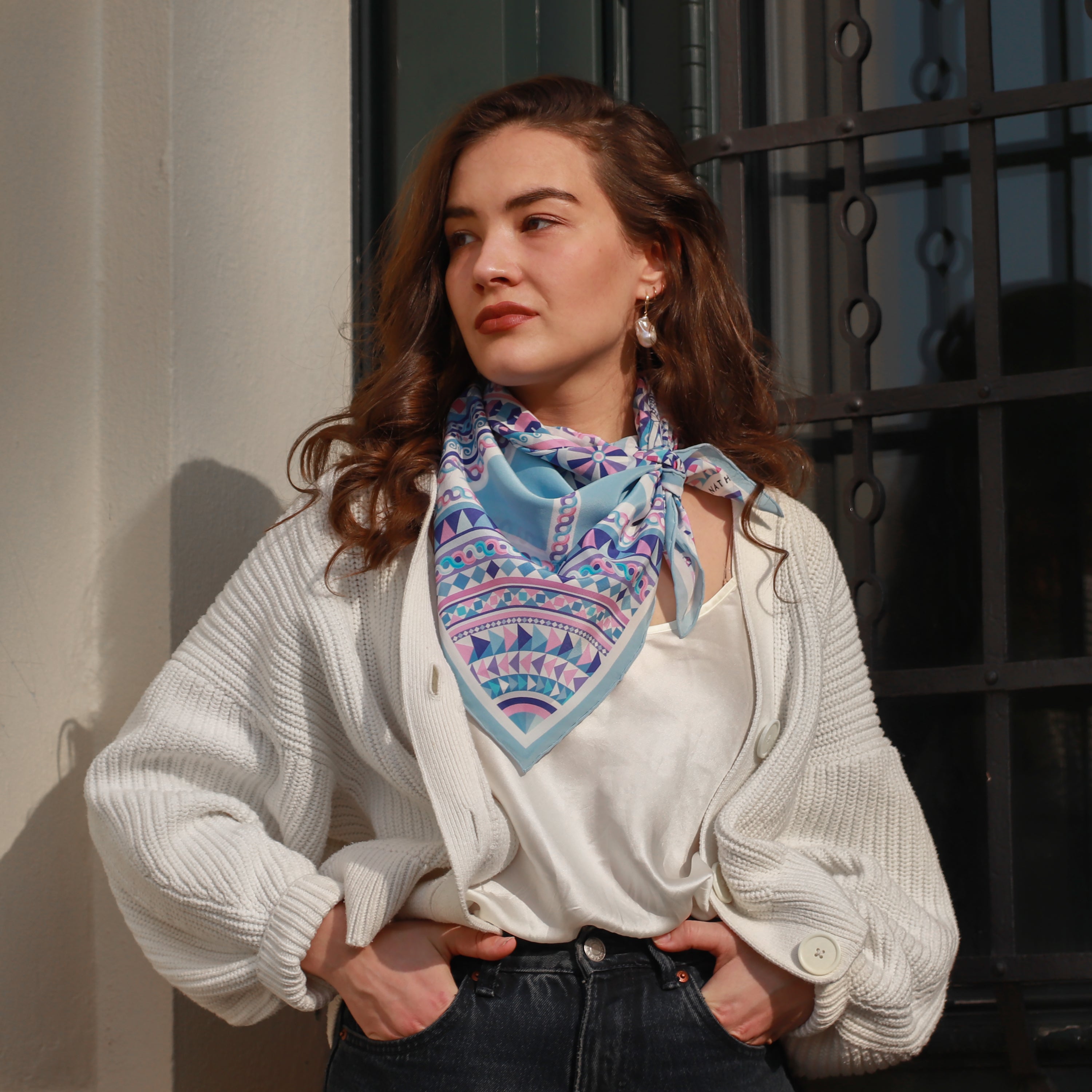 Model wearing the Basilica Zaffiro silk scarf styled around the neck with a white blouse.