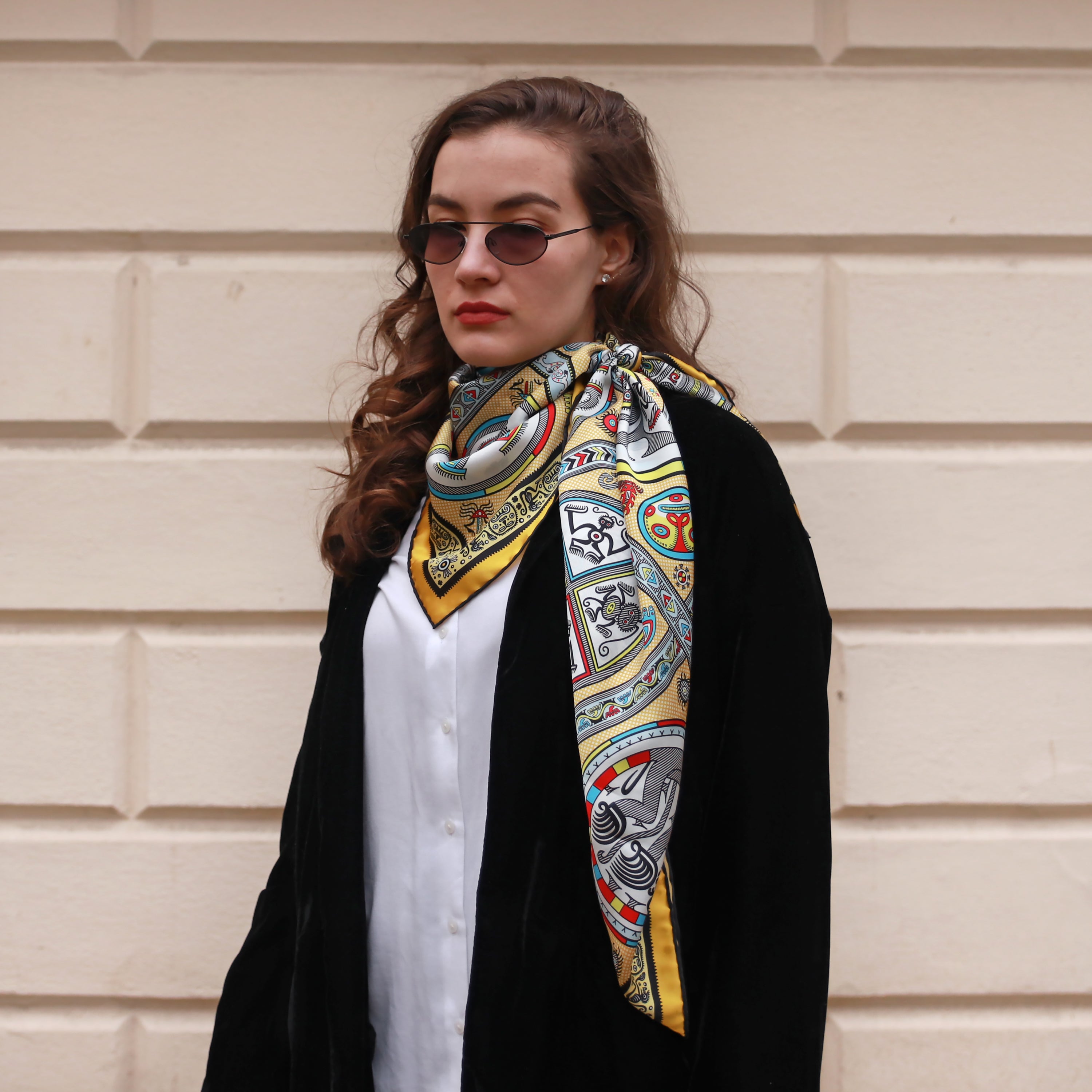 Model wearing the Gran Coclé Royal silk scarf draped over the shoulders with a black coat.