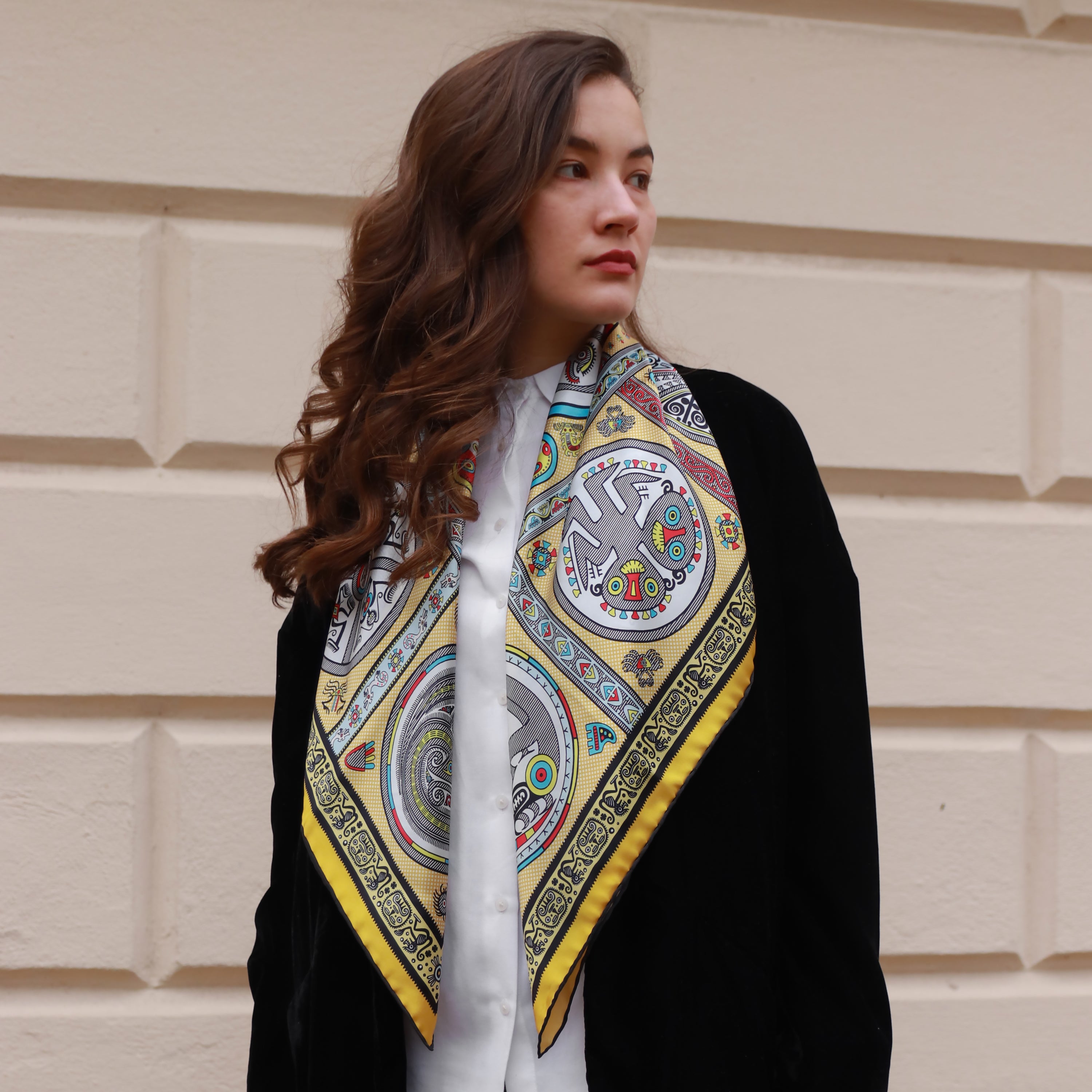 Model wearing the Gran Coclé Royal silk scarf styled around the neck with a black coat.