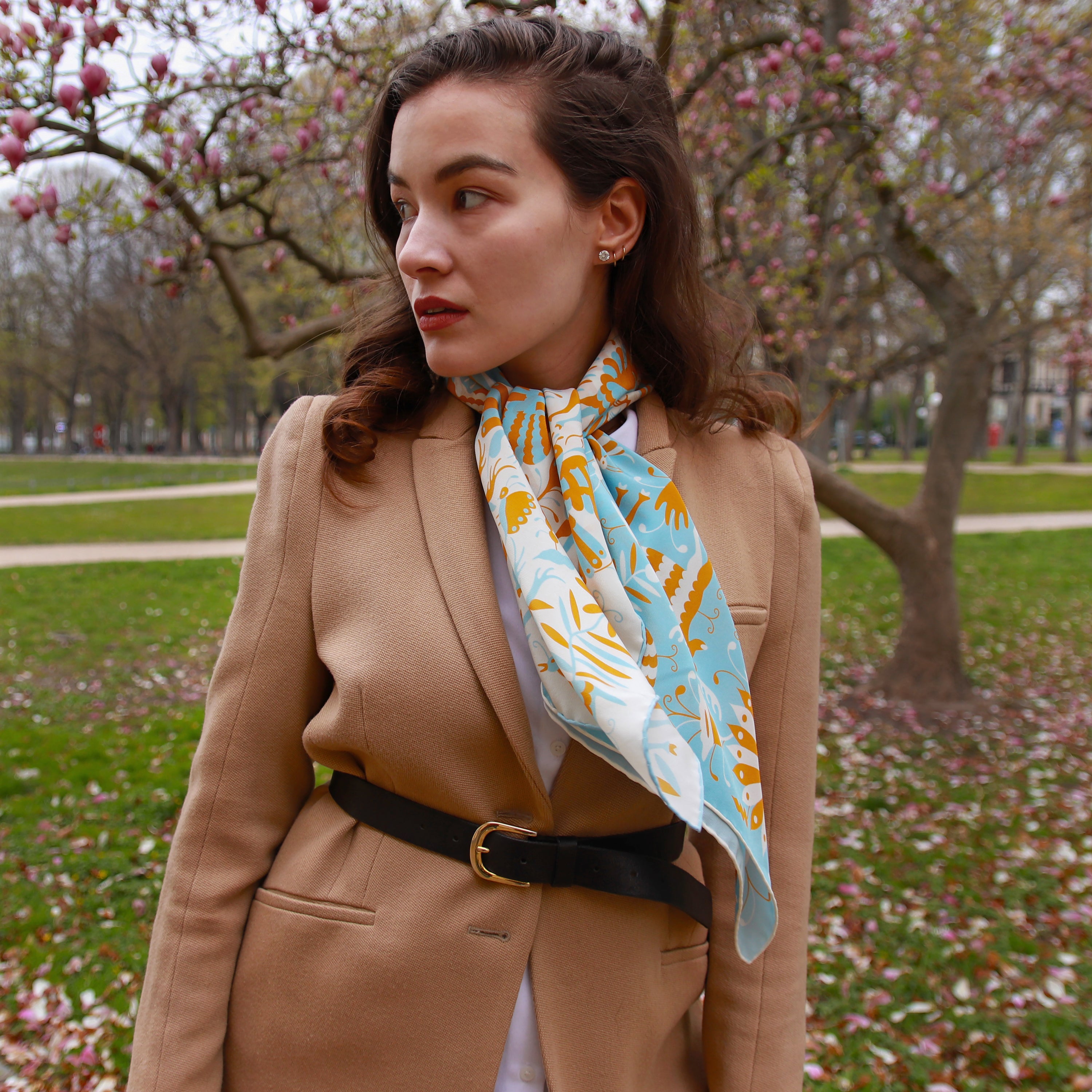 Model wearing the Noé Miroir silk scarf draped down the front with a camel coat.