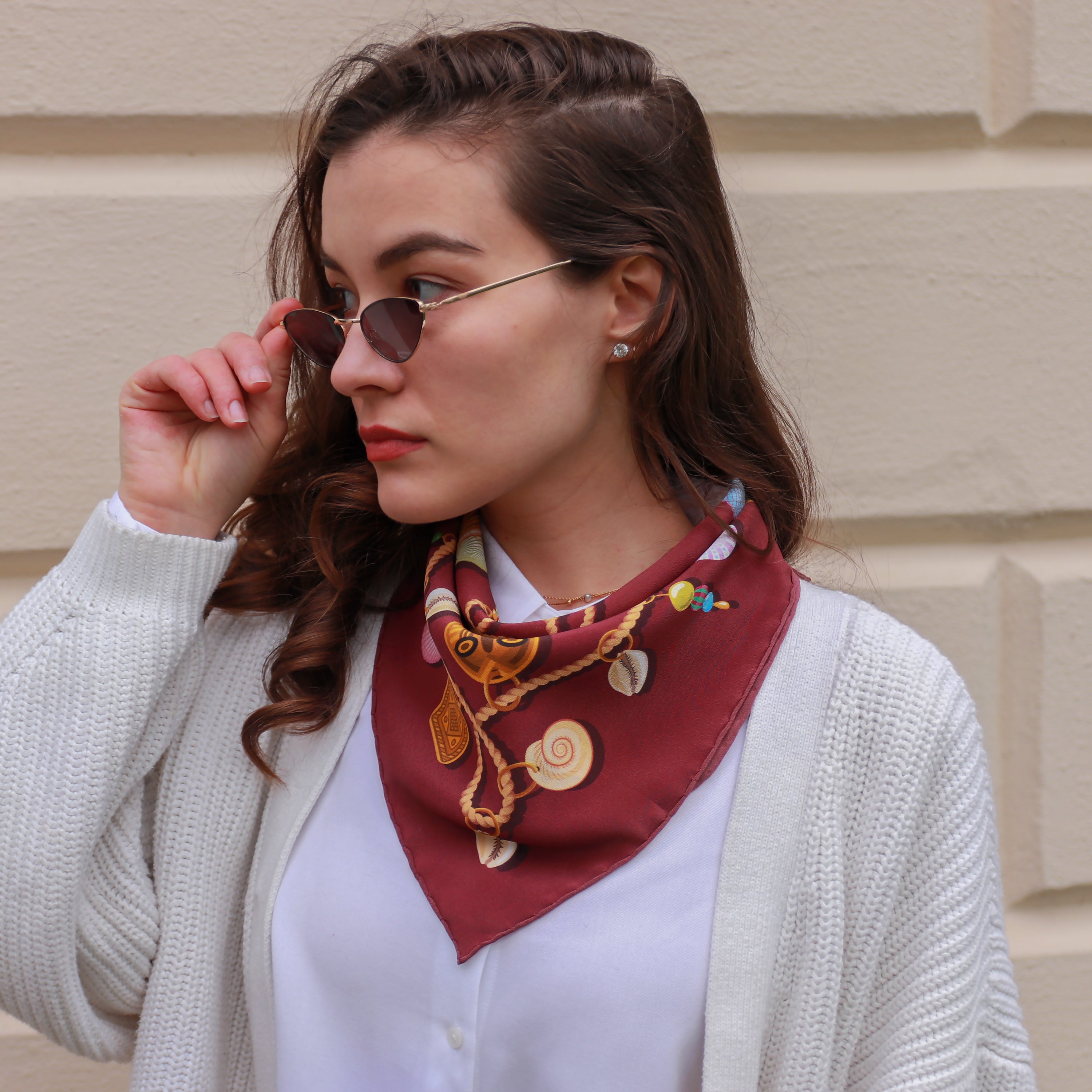 Model wearing the Kauri Rubis silk bandana scarf styled around the neck with a white blouse.