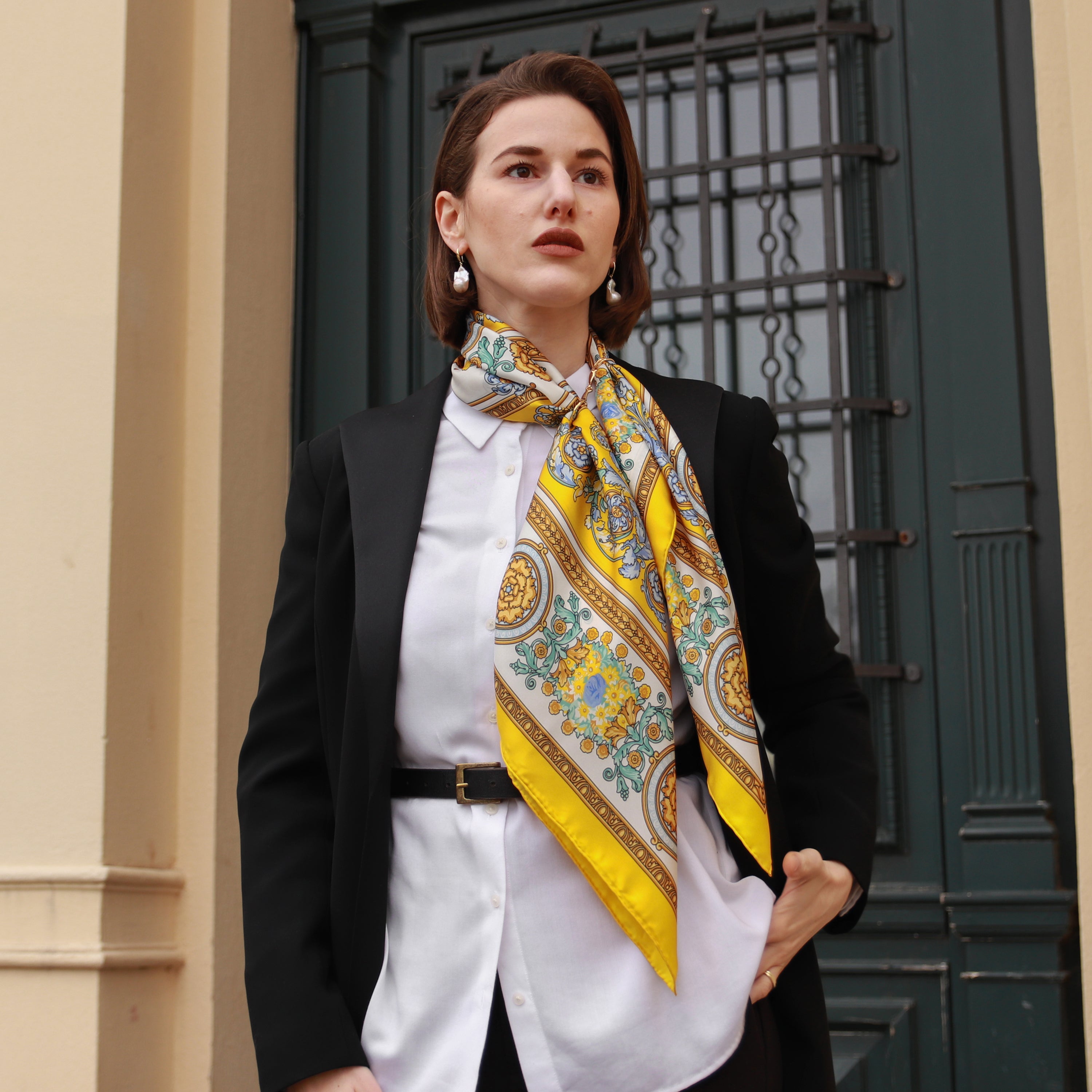 Model wearing the Rococo Limone silk scarf styled around the neck with a black blazer and white blouse.