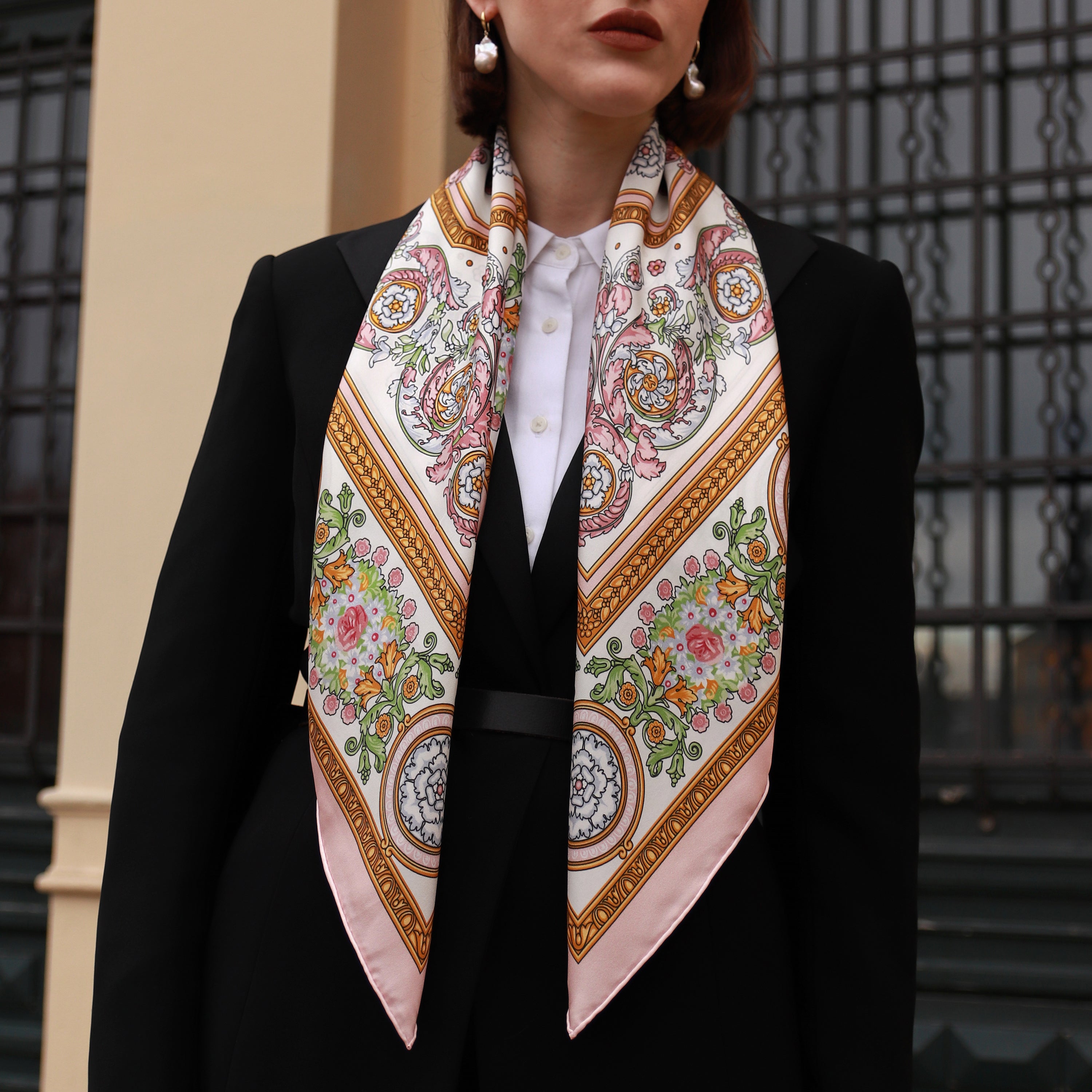 Model wearing the Rococo Rosa silk scarf draped down the front with a black blazer.