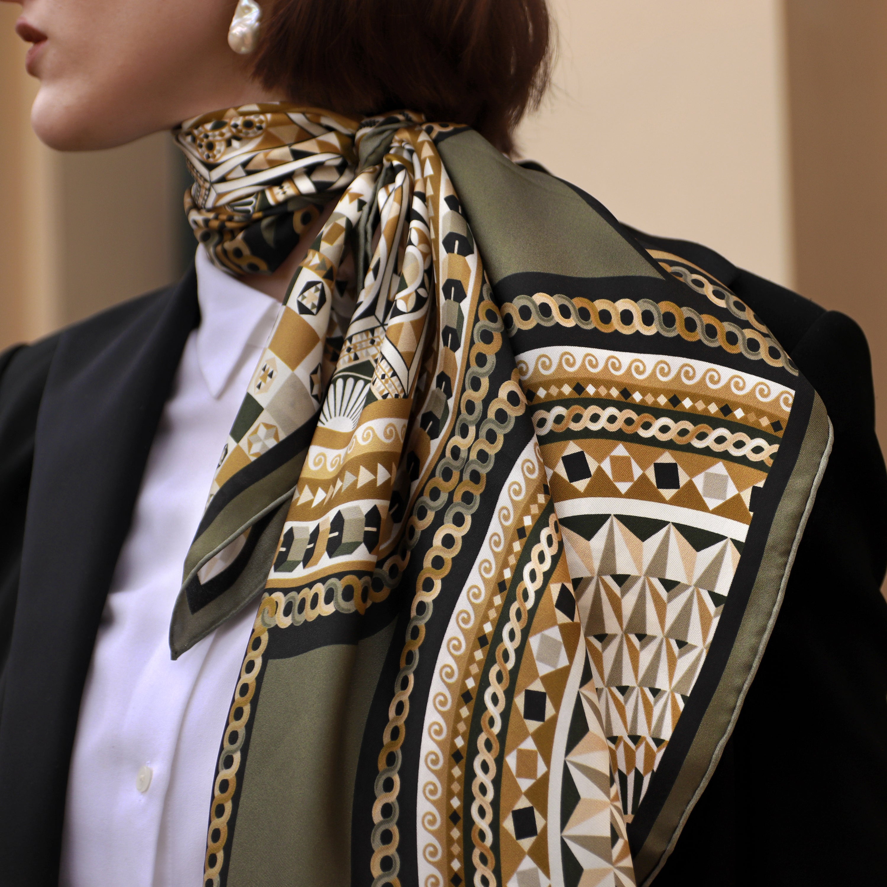 Model wearing the Basilica Nero silk scarf draped down the back with a black blazer.