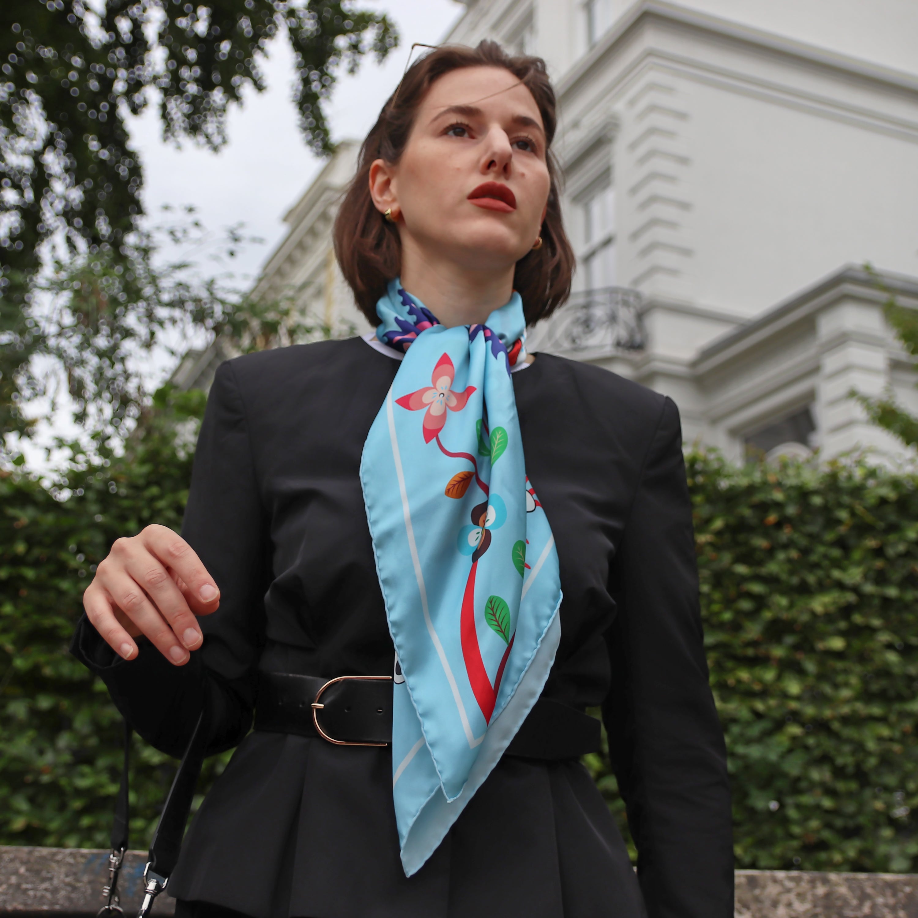 Model wearing the Abomey Maya silk scarf styled around the neck with a black blazer.