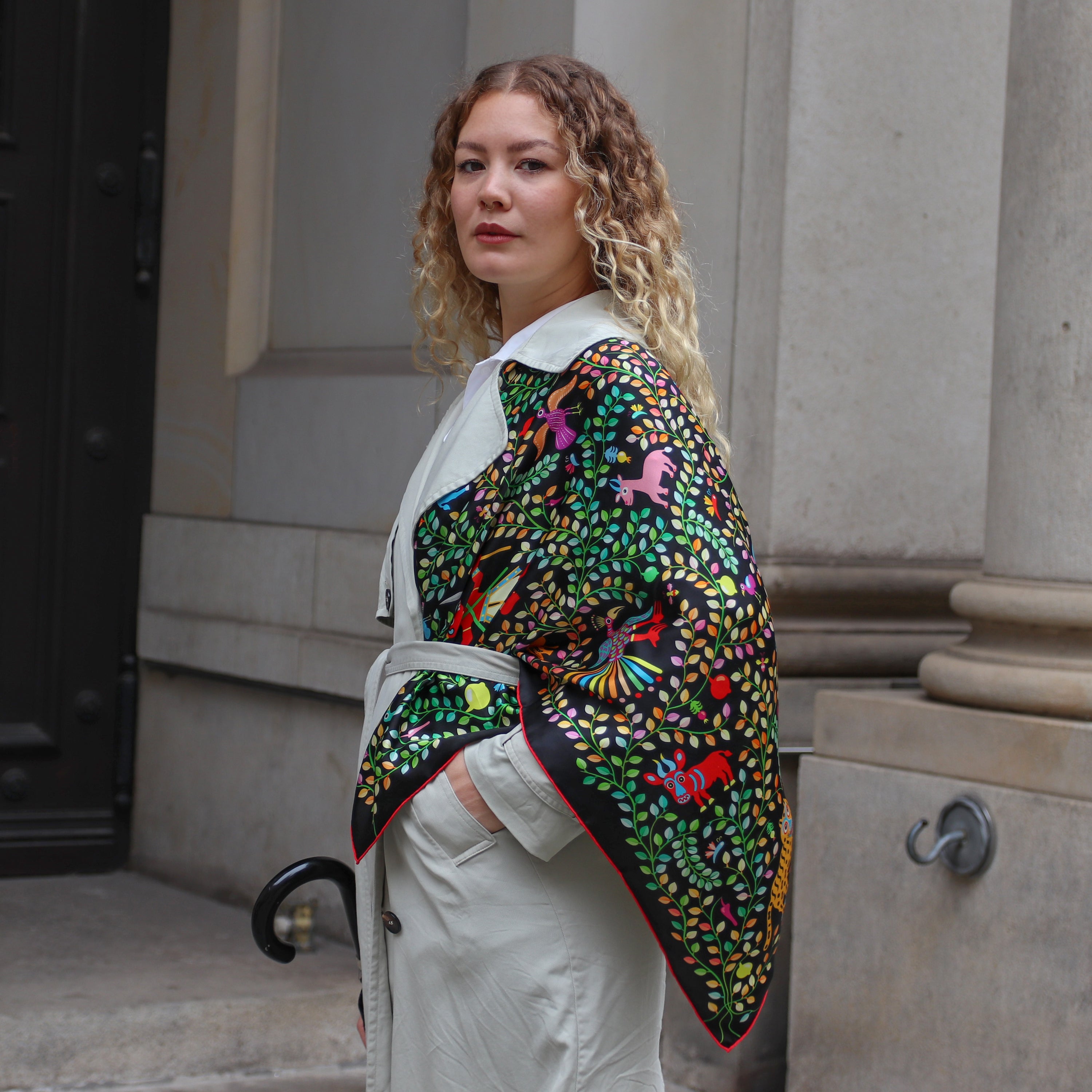 Model wearing the Kings of Dahomey Original silk scarf draped over the shoulders with a light trench coat.