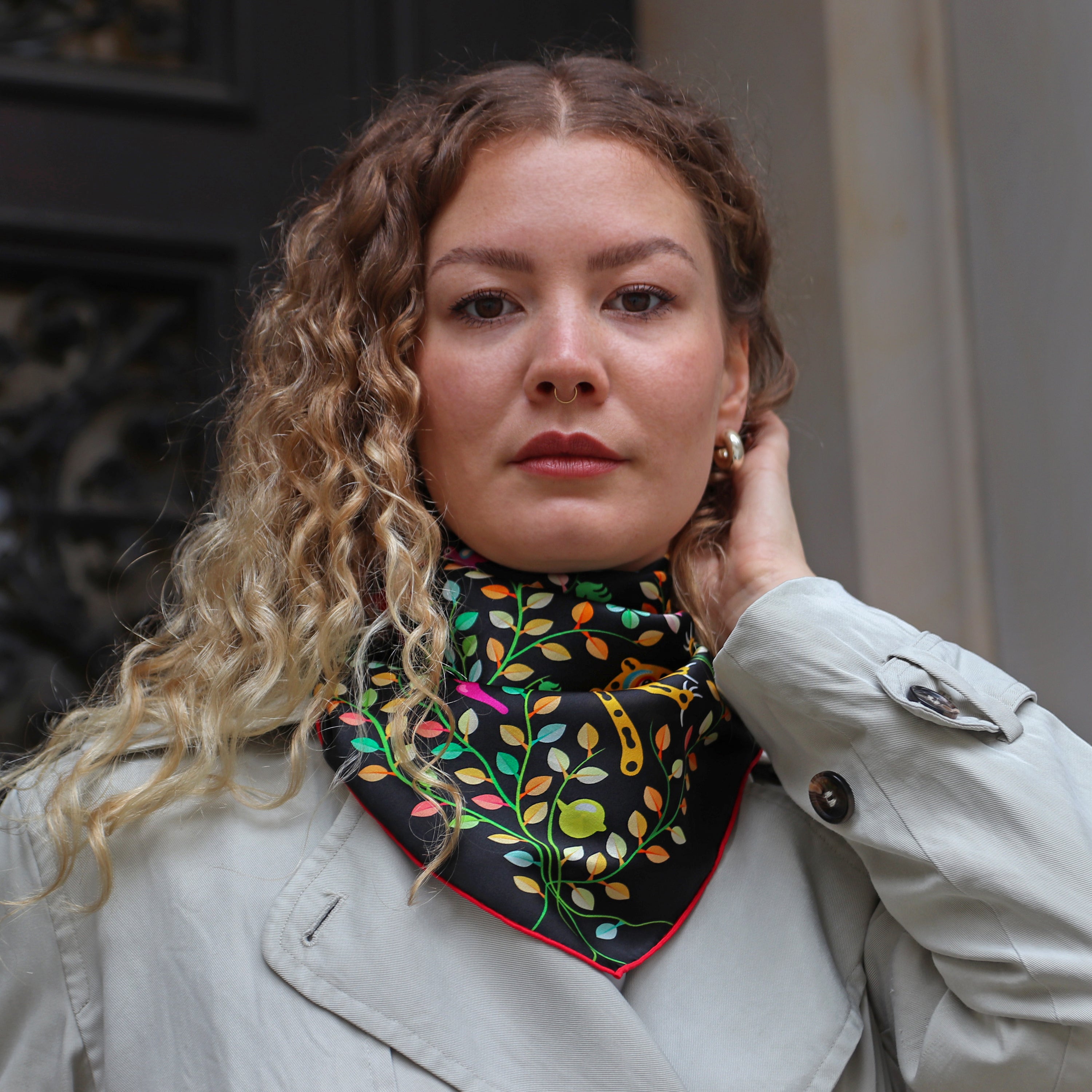 Model wearing the Kings of Dahomey Original silk scarf styled around the neck with a light trench coat.