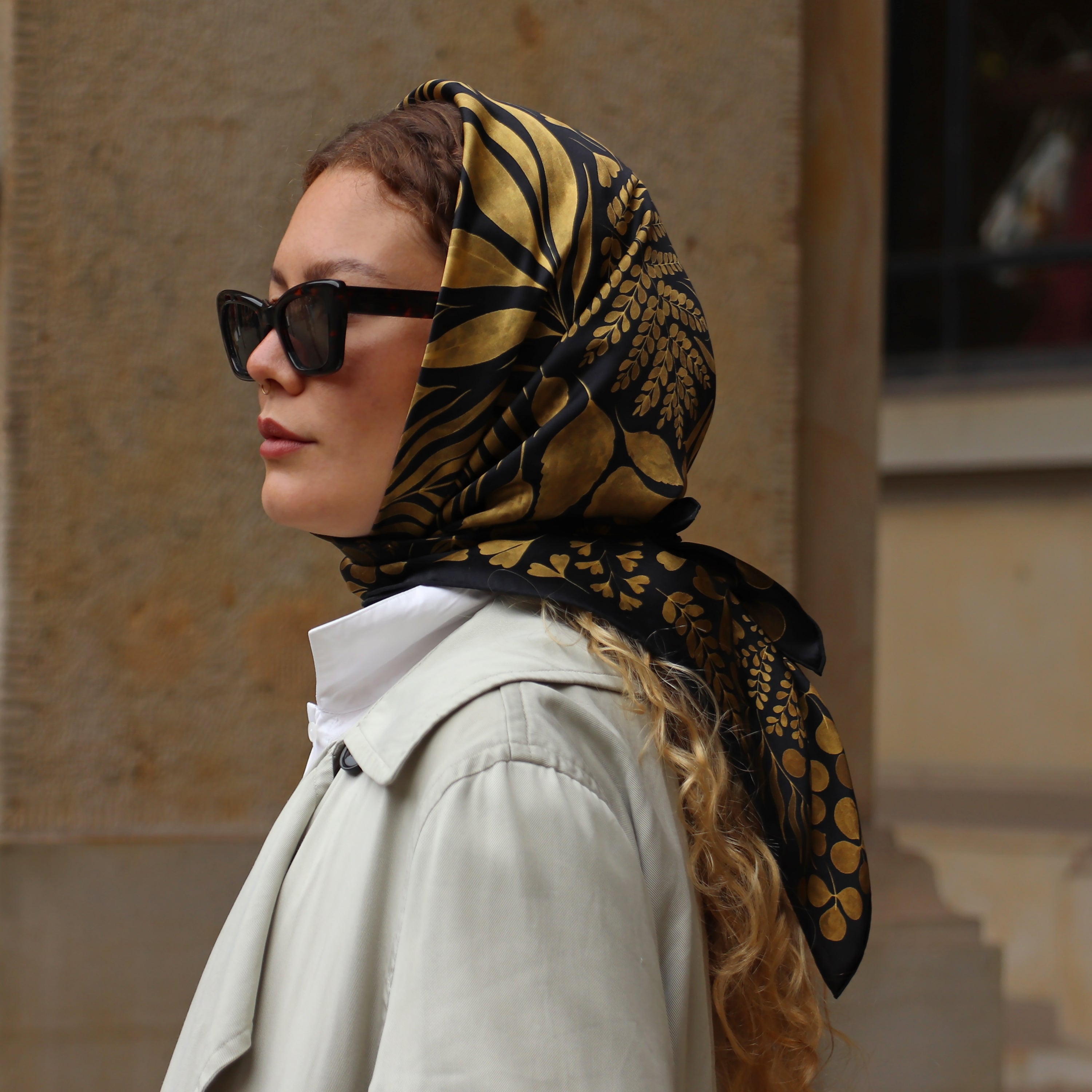 Model wearing the Foglie d'Oro silk scarf styled as a headscarf.