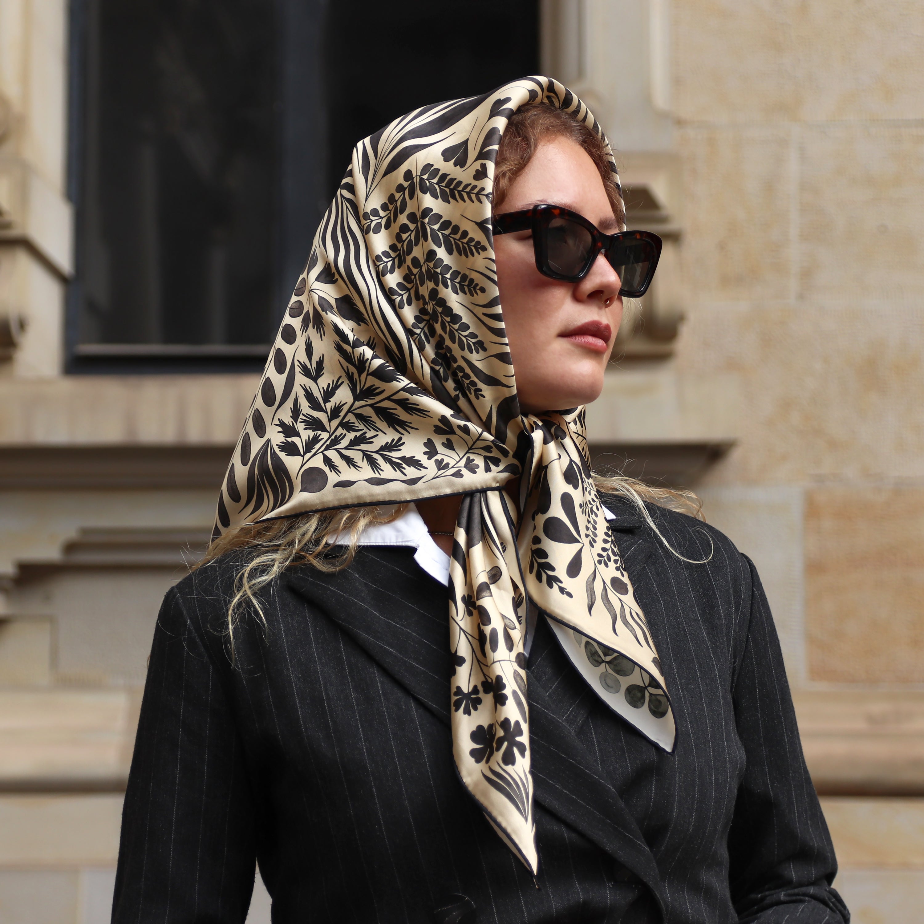 Model wearing the Foglie Crema silk scarf styled as a headscarf.