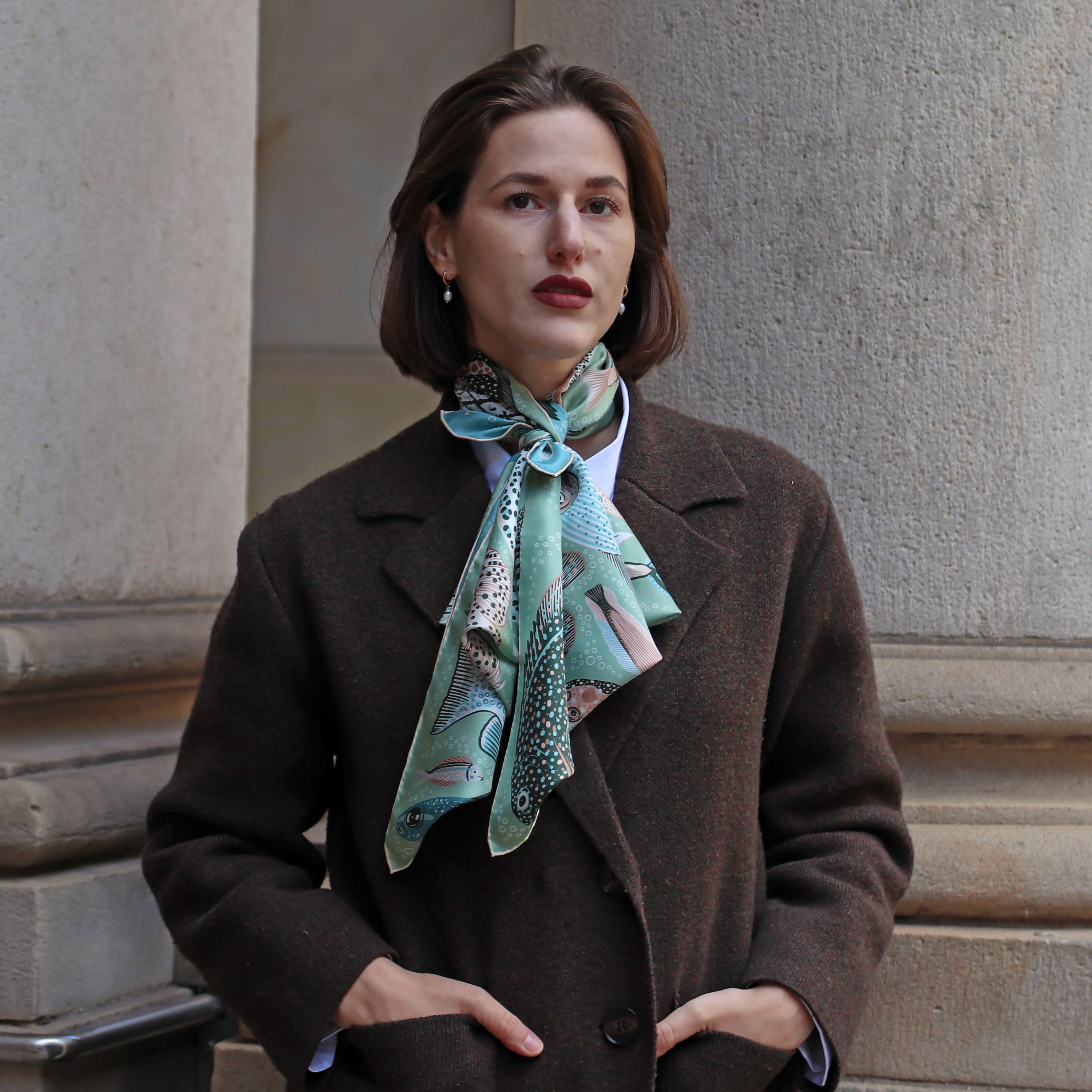 Model wearing the Pesce Acqua double-sided silk scarf styled around the neck with a dark coat.