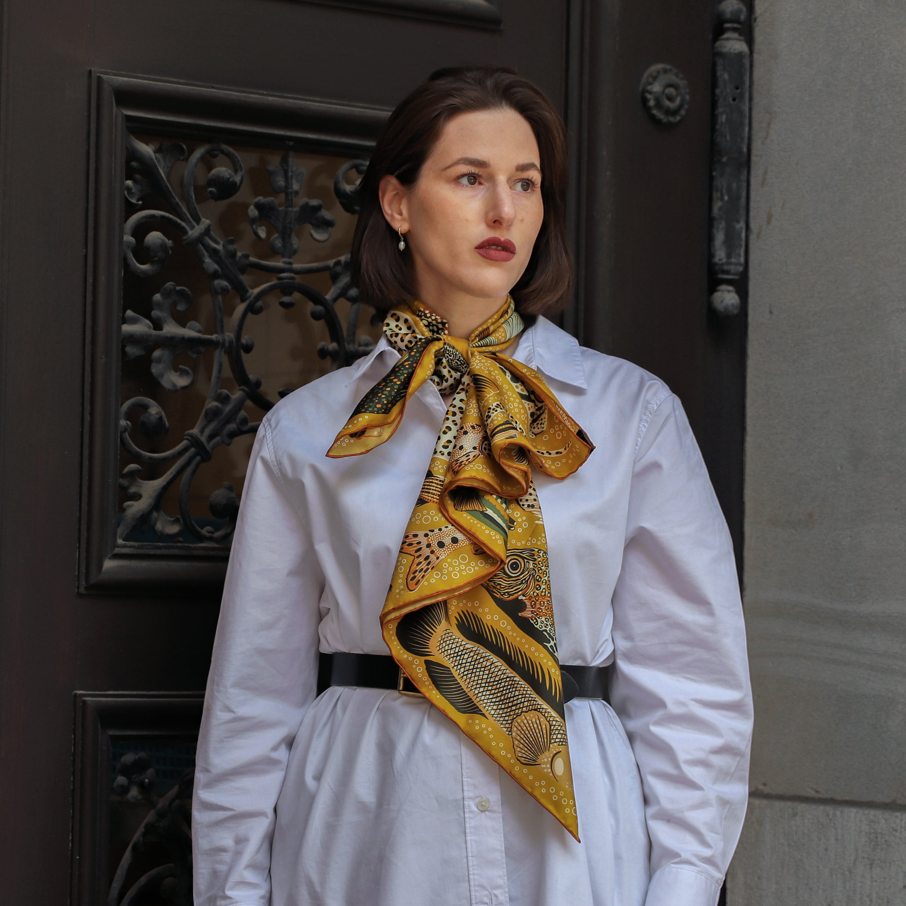 Model wearing the Pesce Miele silk scarf styled around the neck with a white shirt.